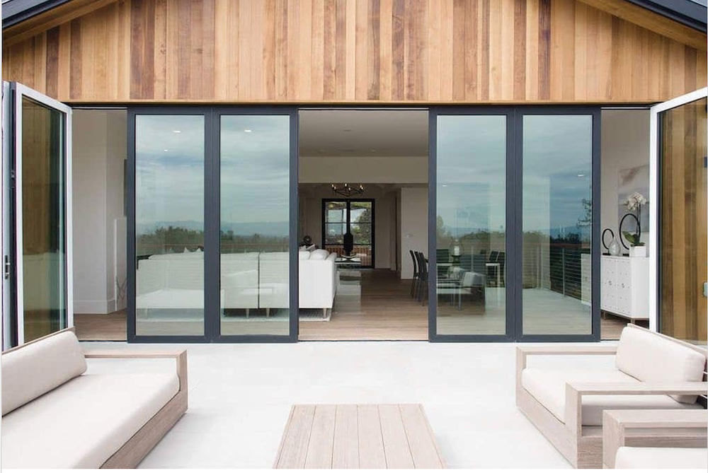 sliding glass doors open to patio with white outdoor furniture by Panoramic Doors