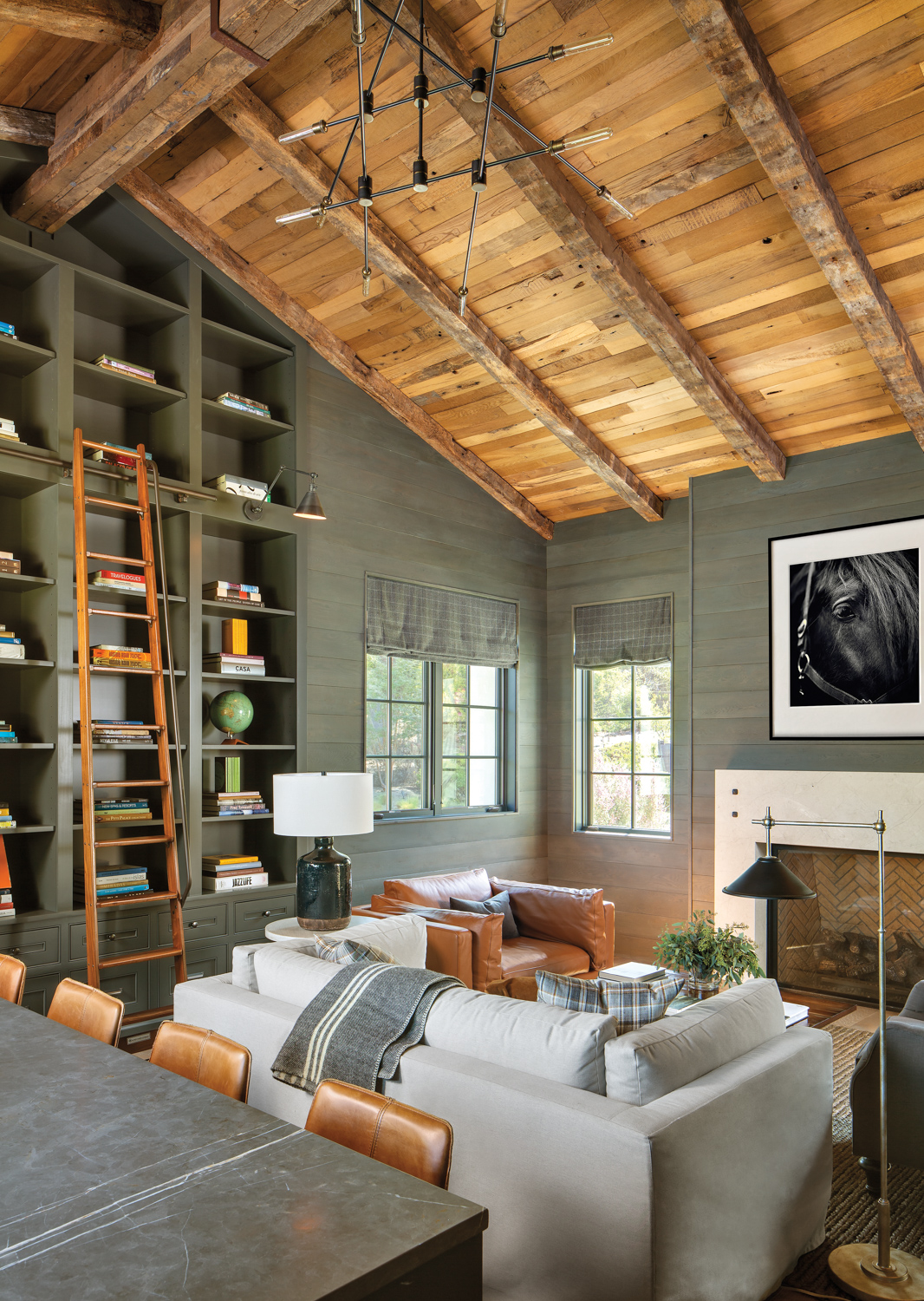 Library with charcoal walls, natural-wood paneled ceilings and white and tan leather seating