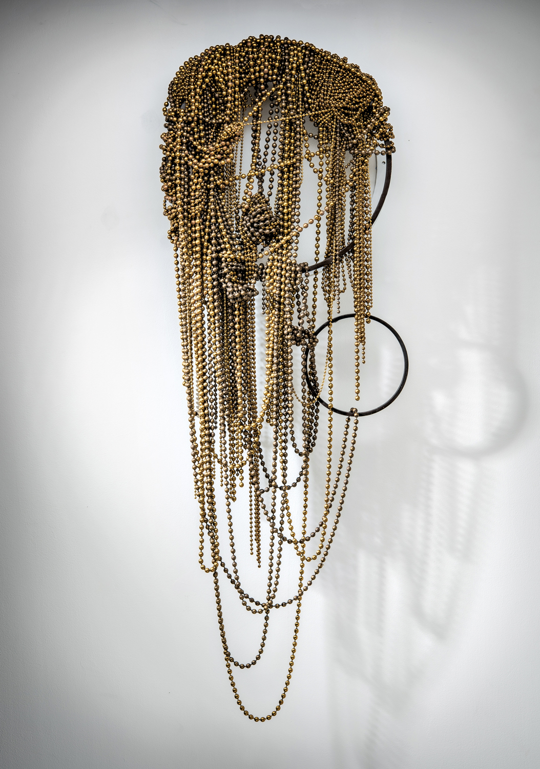 Wall hanging made of gold industrial ball chain and metal hoops.