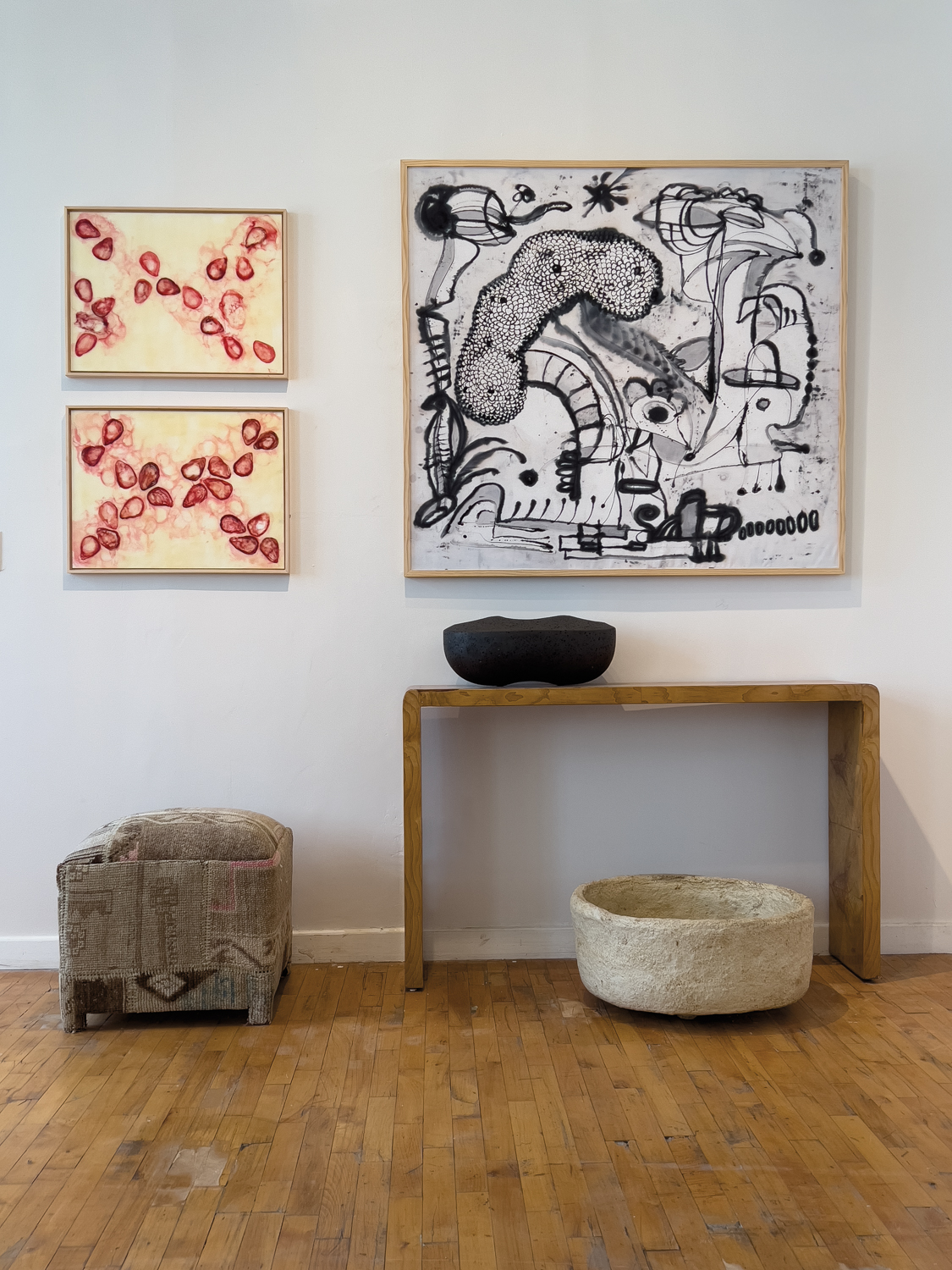 Abstract artworks hanging above a vintage wood console and vintage ottoman. 