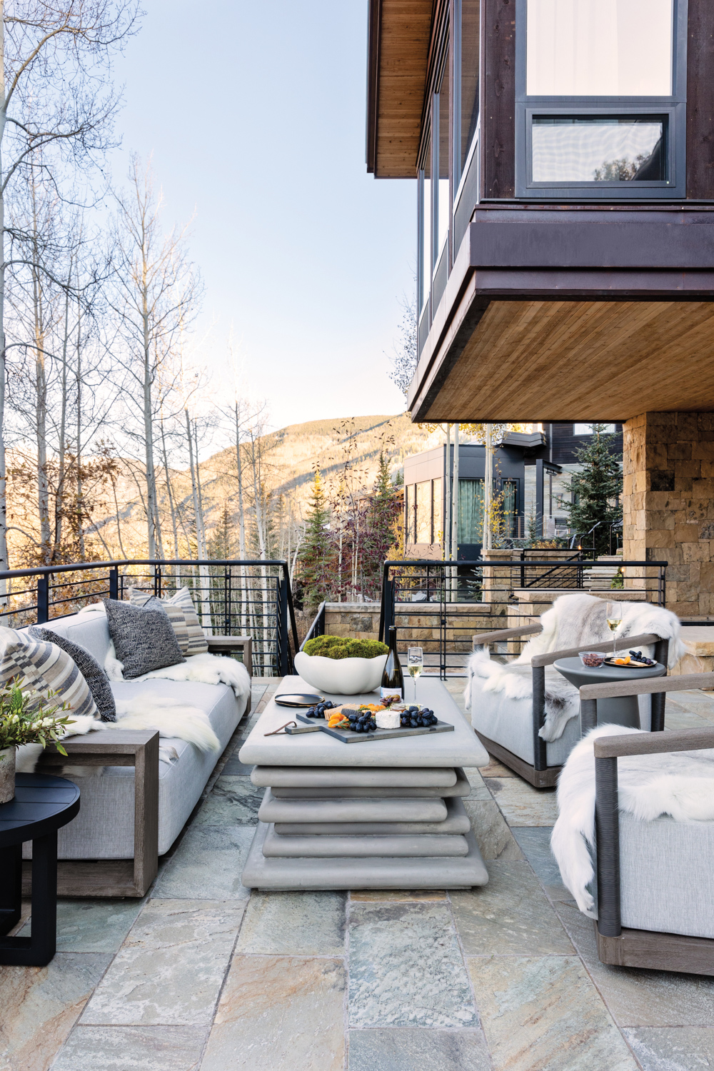 Home deck with stack-stone coffee table, matching sofa and armchairs and mountain views
