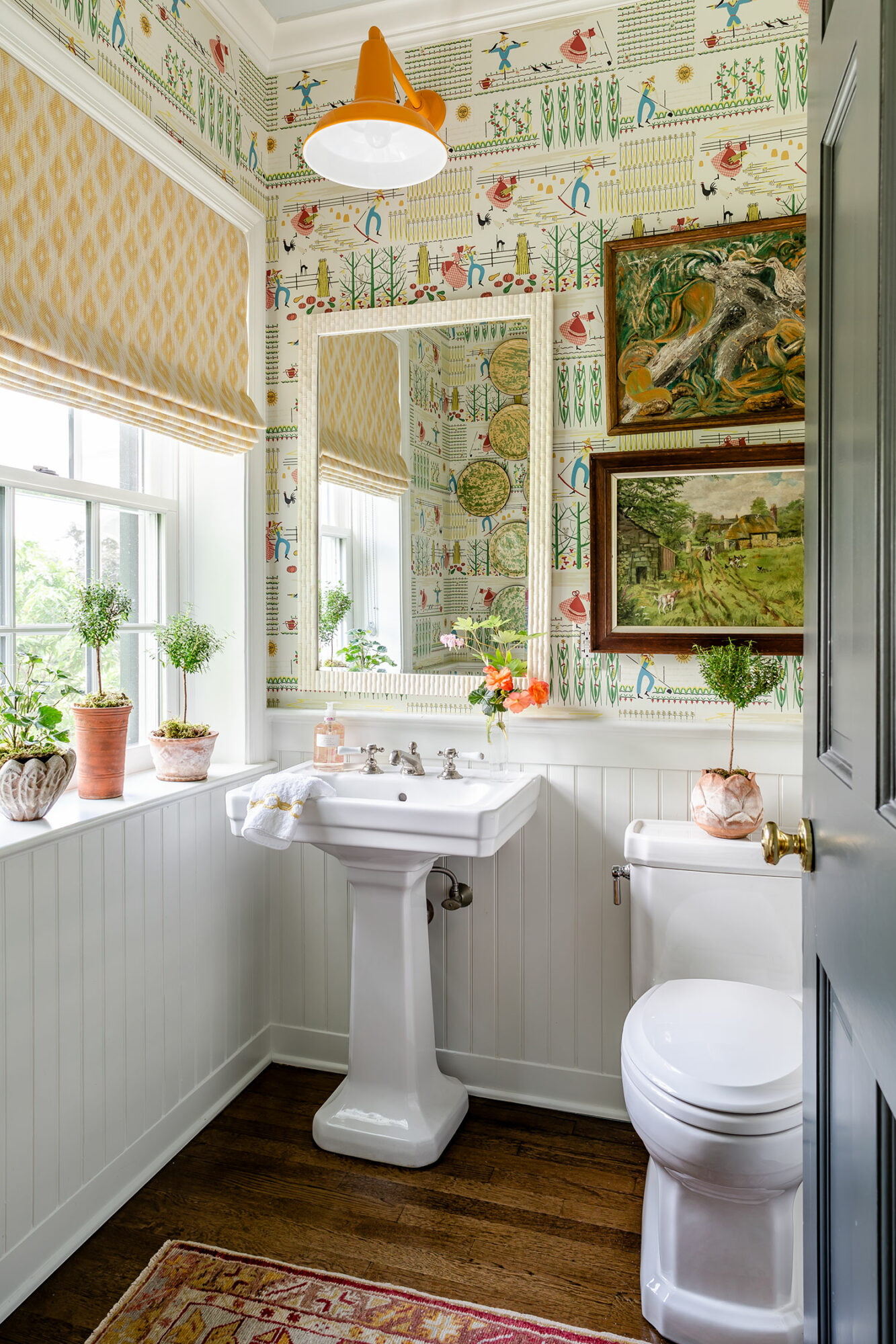 modern traditional take on a maximalist bathroom featuring farmer wallpaper and framed art