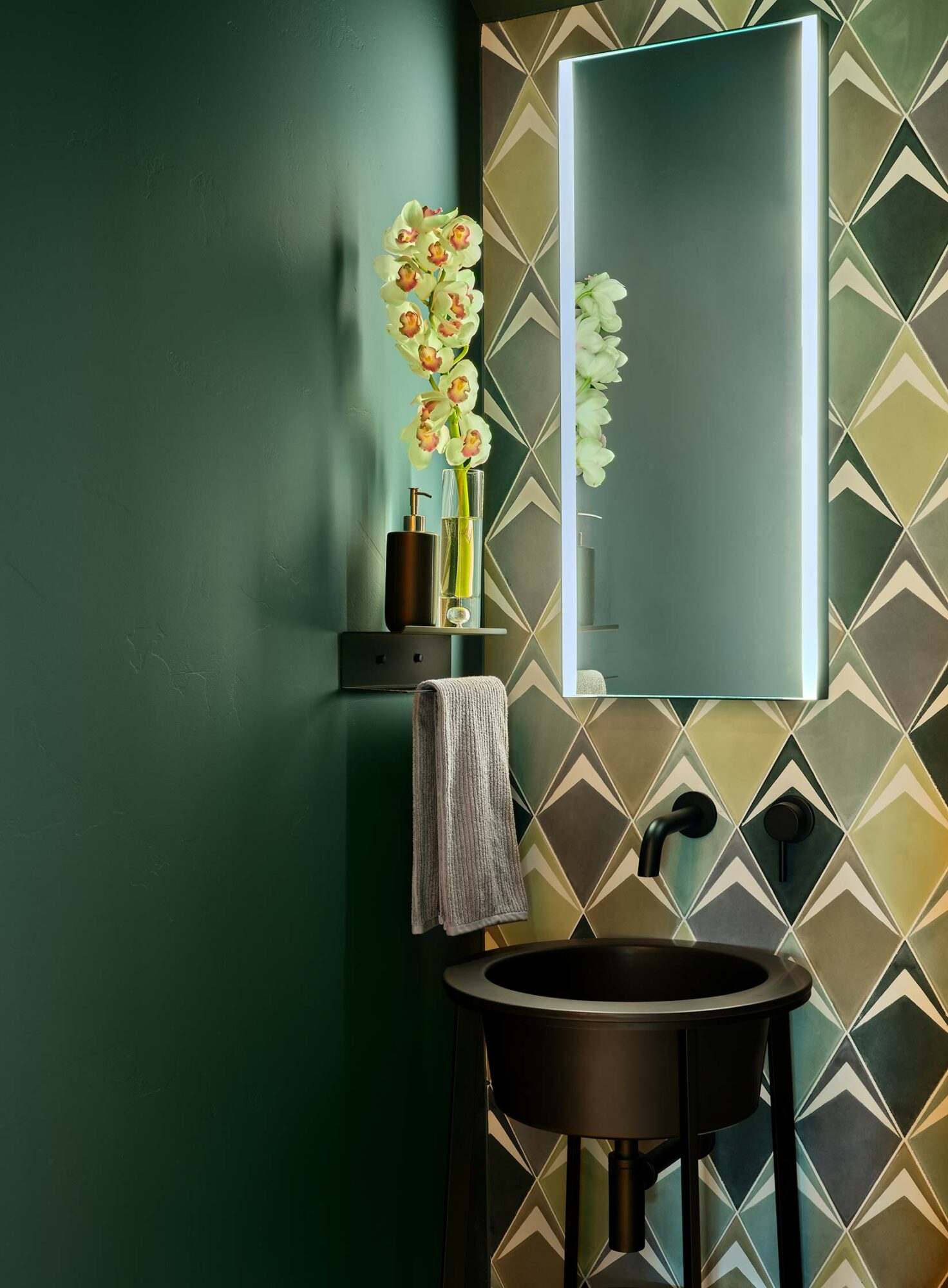 teal green bathroom with small vanity and lime green and brown patterned statement wall 