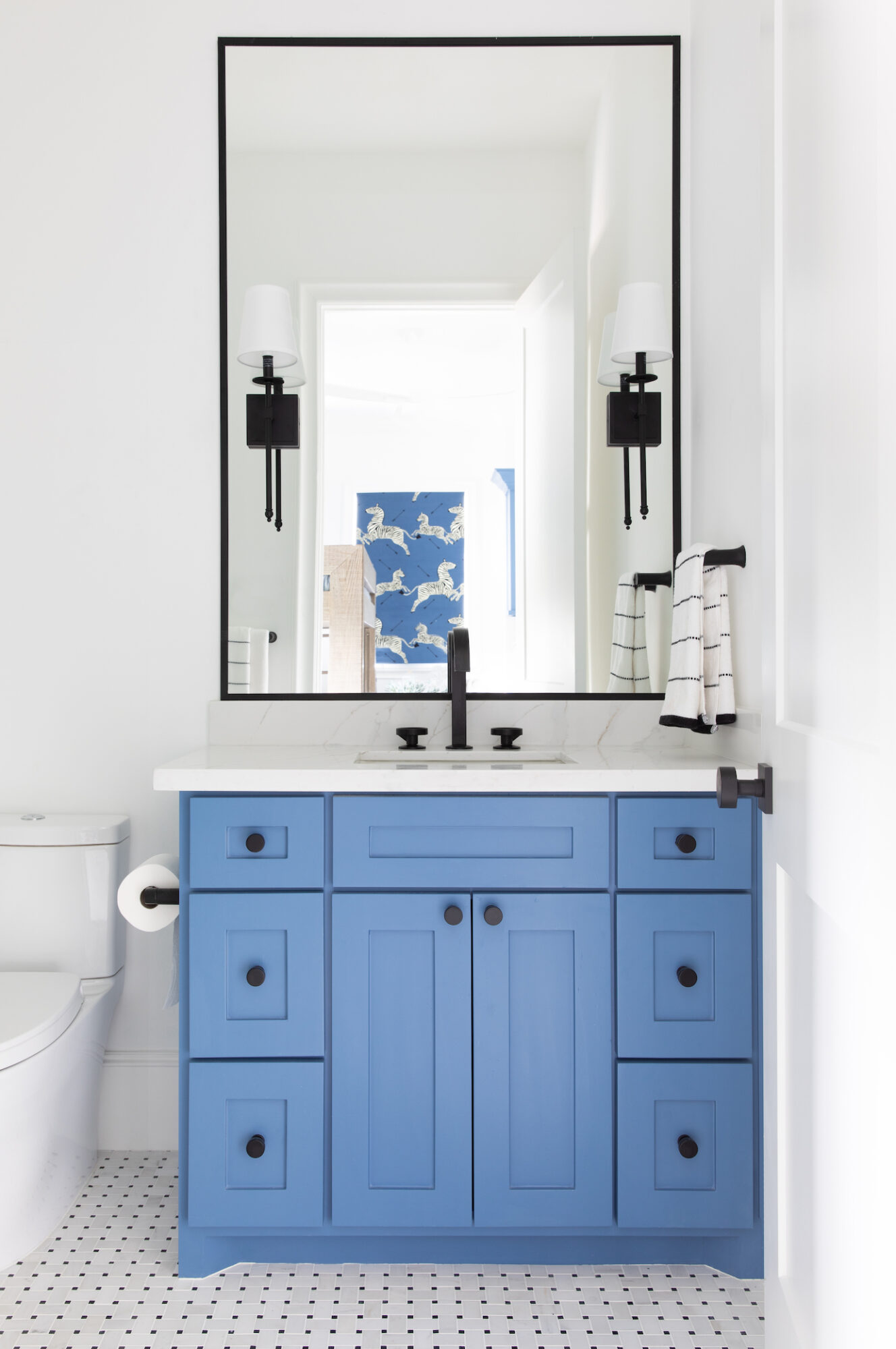 powder bathroom with blue vanity and tile floor