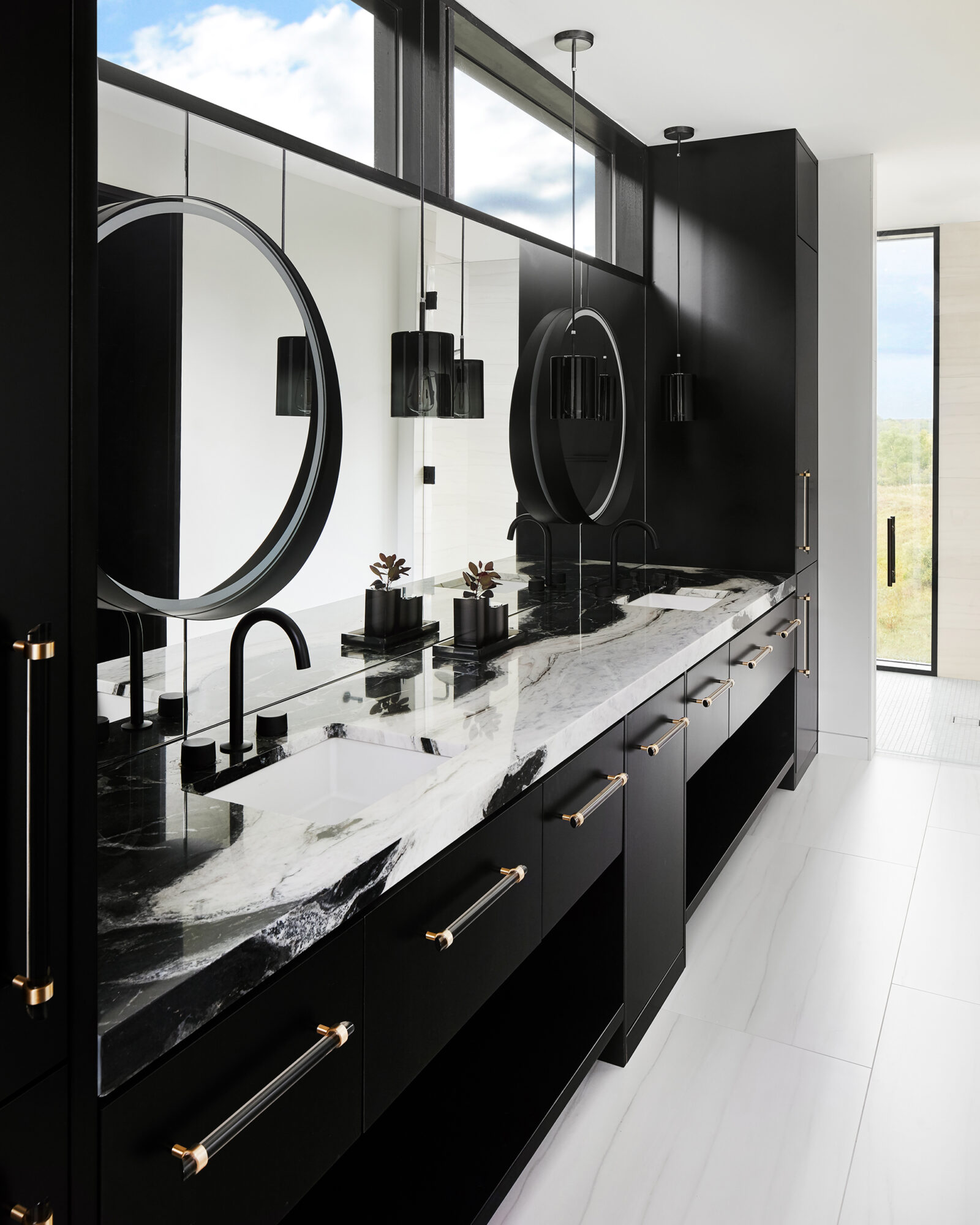 high contrast black and white primary bathroom with circle mirrors and statement stone countertops