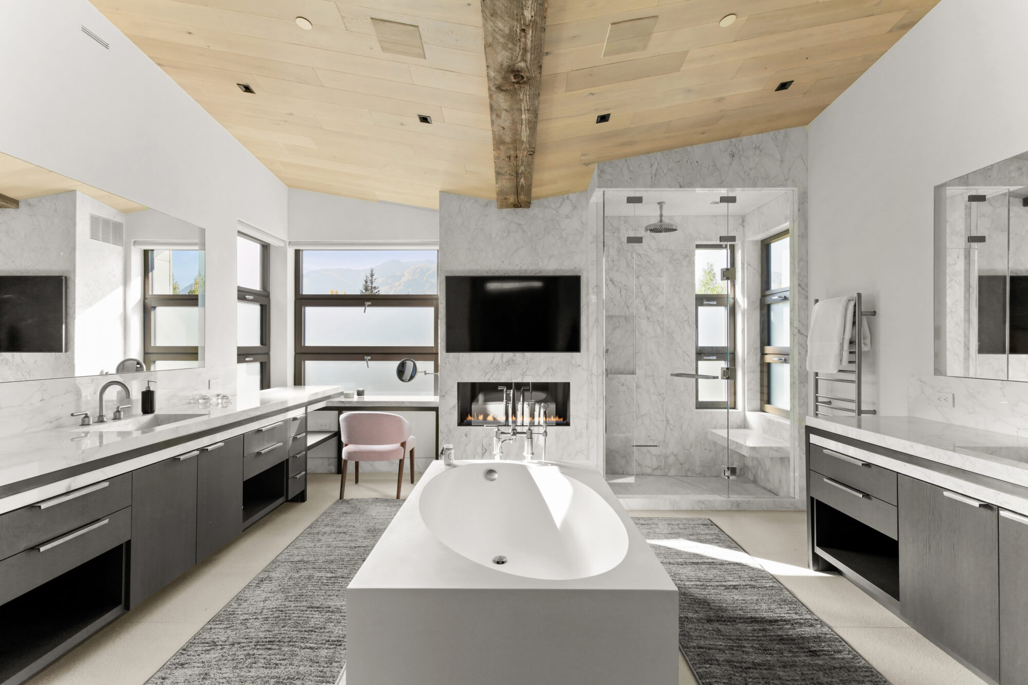 primary bathroom with center tub, wood beams and natural light