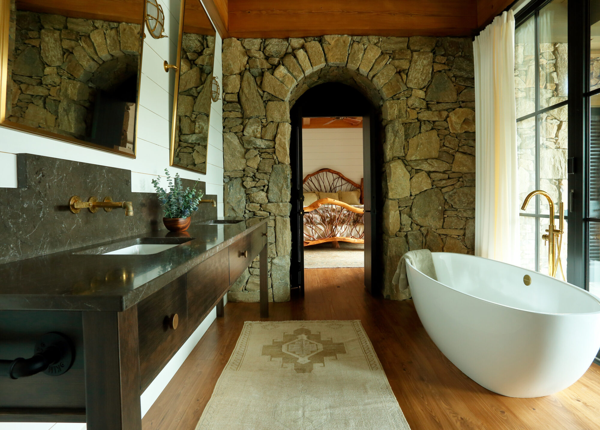 rustic modern bathroom with cypress wood flooring, stone entry and freestanding tub