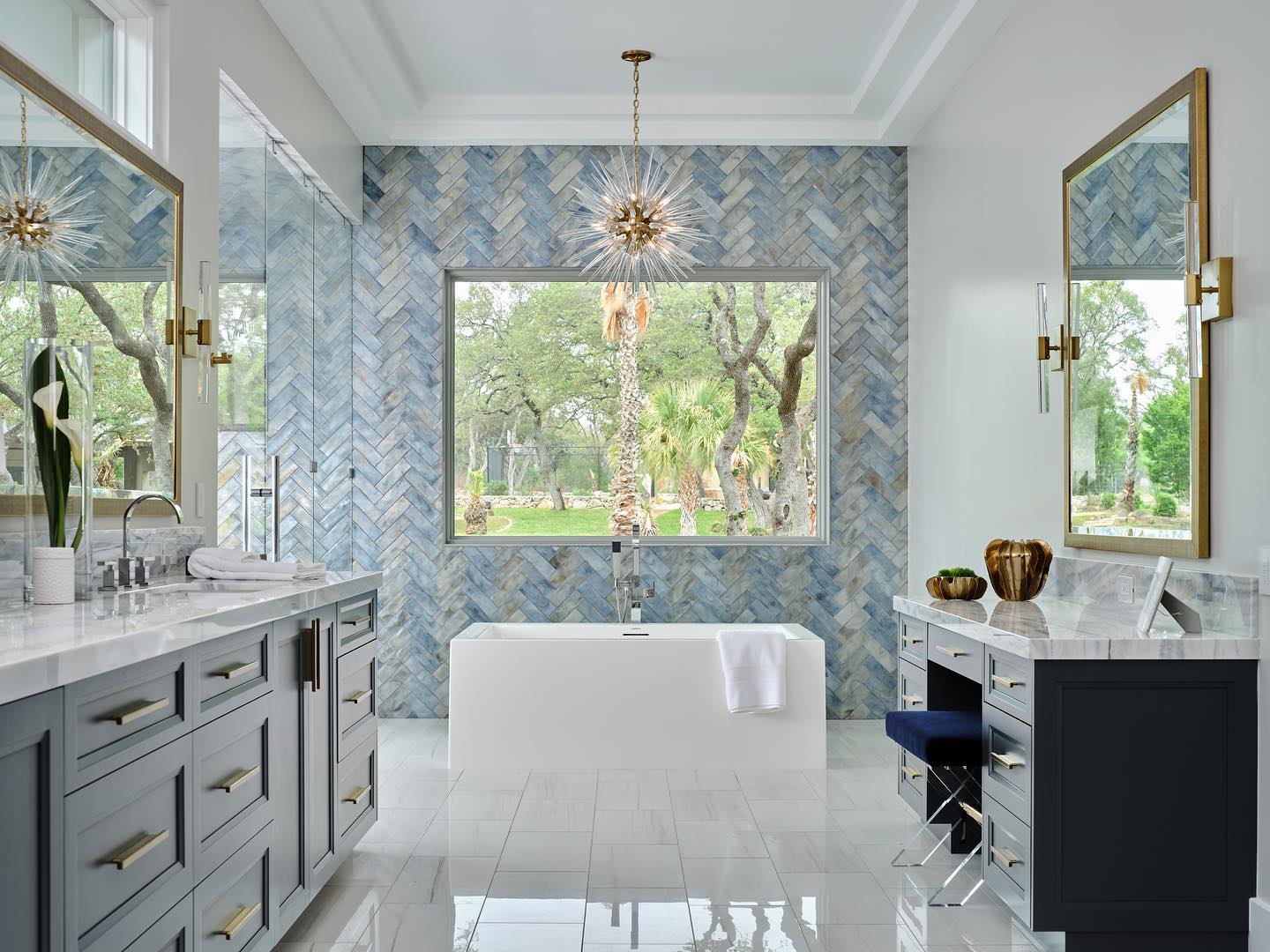Soaking tub with blue patterned walls and chandelier.