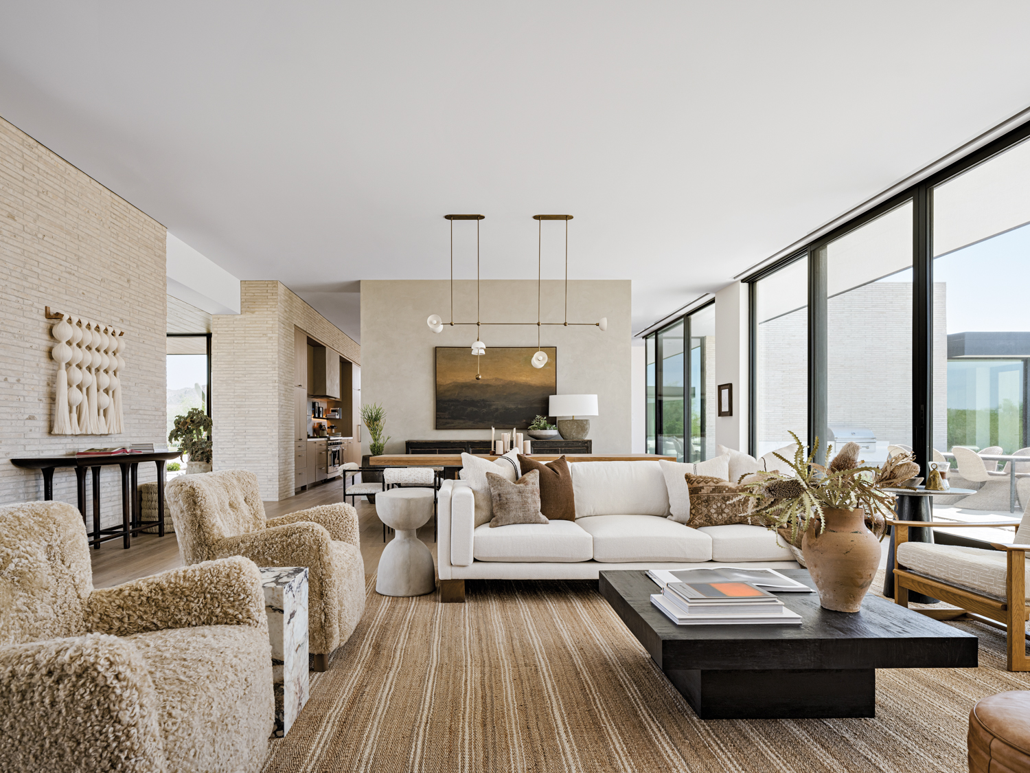 a neutral great room with two tan furry chair, a white couch and a large black coffee table