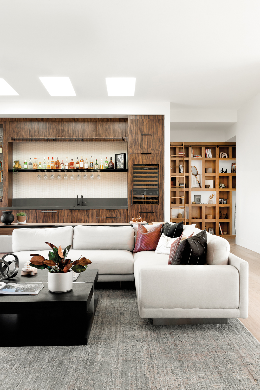 living room with a white sectional and a bar and bookcase in the background