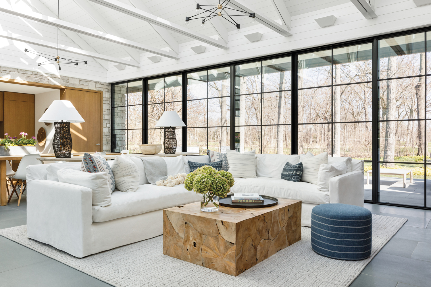 living room with white sectional, wood coffee table and floor-to-ceiling black-steel framed windows