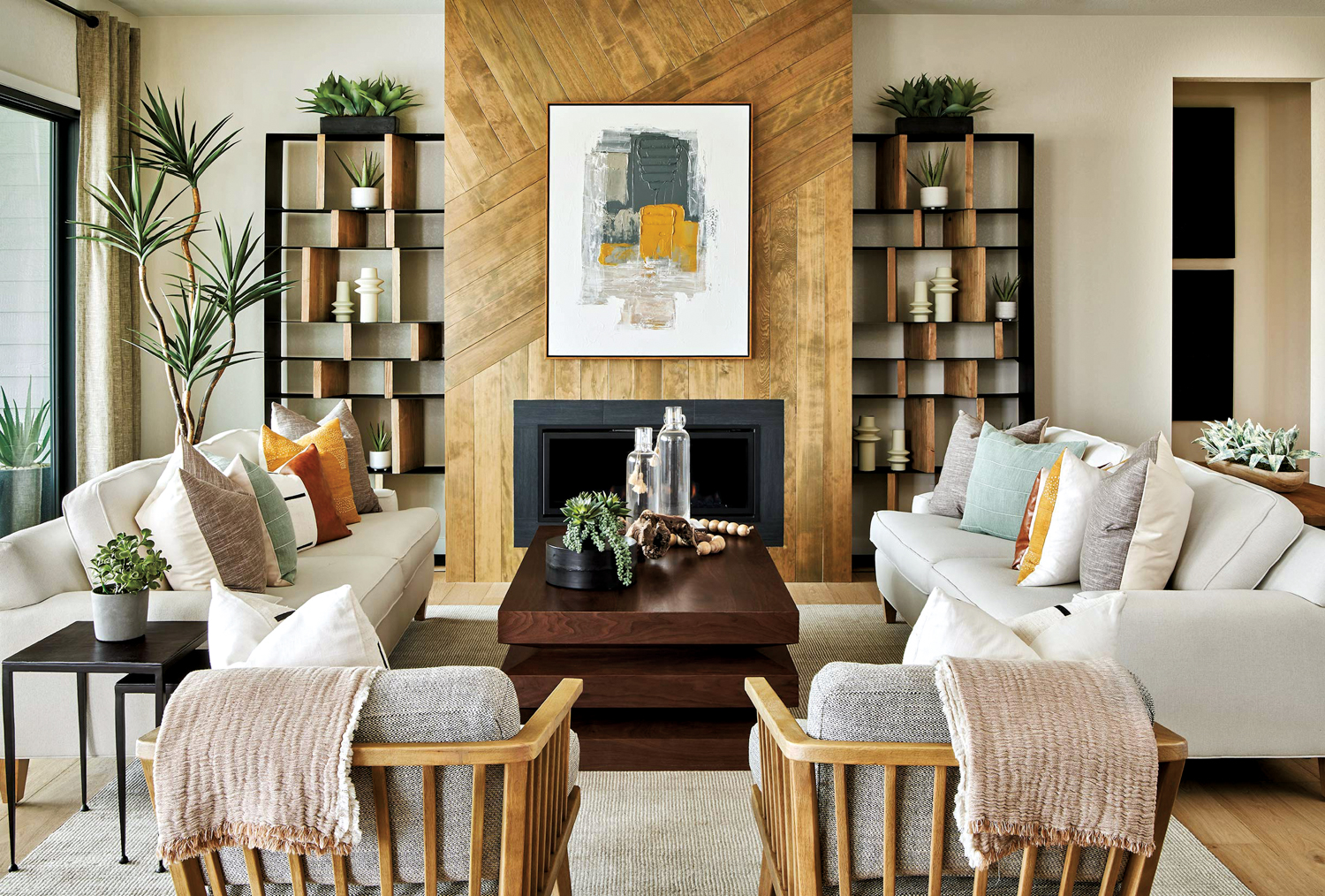 living room with two matching pairs of armchairs and sofas facing each other, a dark-wood coffee table and artwork hanging above a fireplace