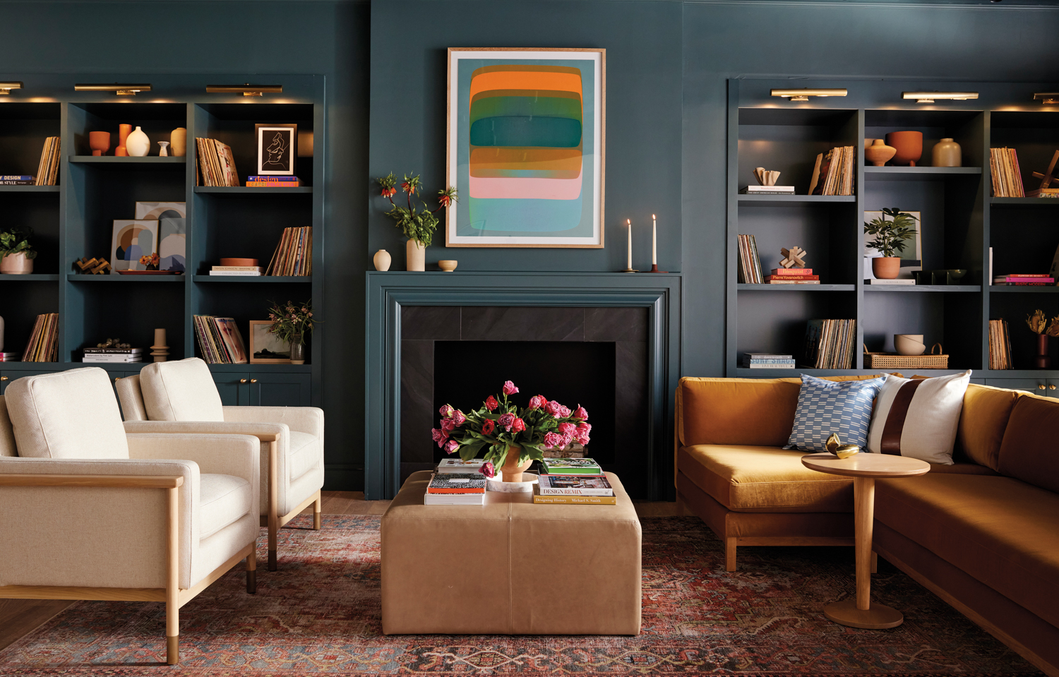 living room with dark-blue walls and a colorful abstract artwork above the fireplace between built-in bookshelves