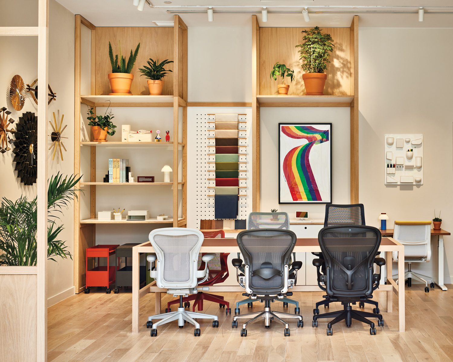 three desk chairs at a table facing shelving at Herman Miller store