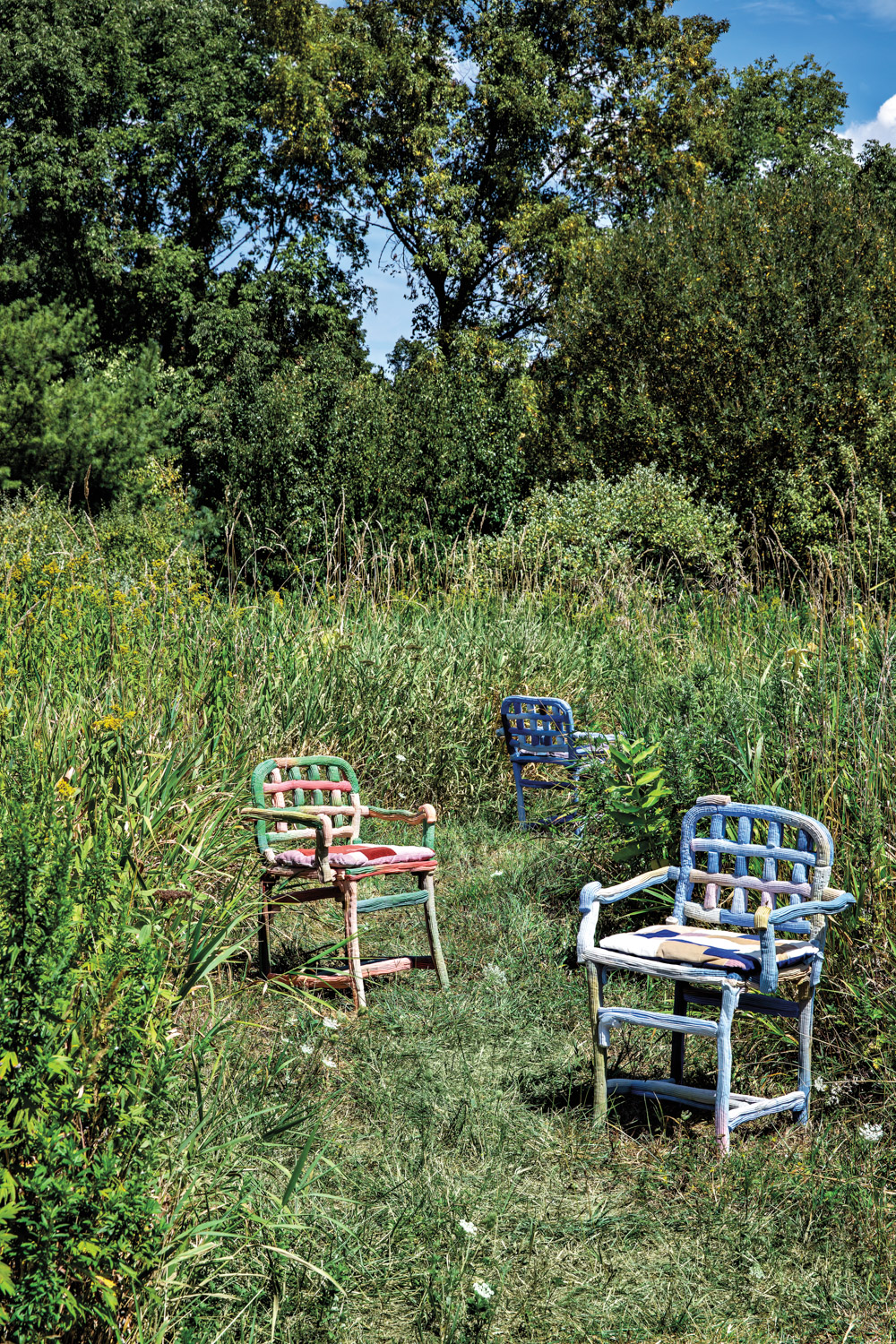 colorful plastic Baroque Chairs topped with corduroy patchwork cushions sitting in a field of grass