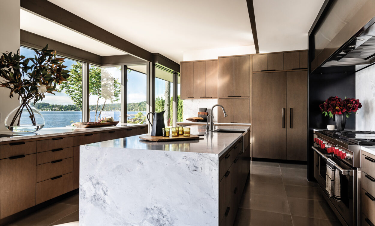 A minimalist kitchen has wood cabinets and a white quartzite island