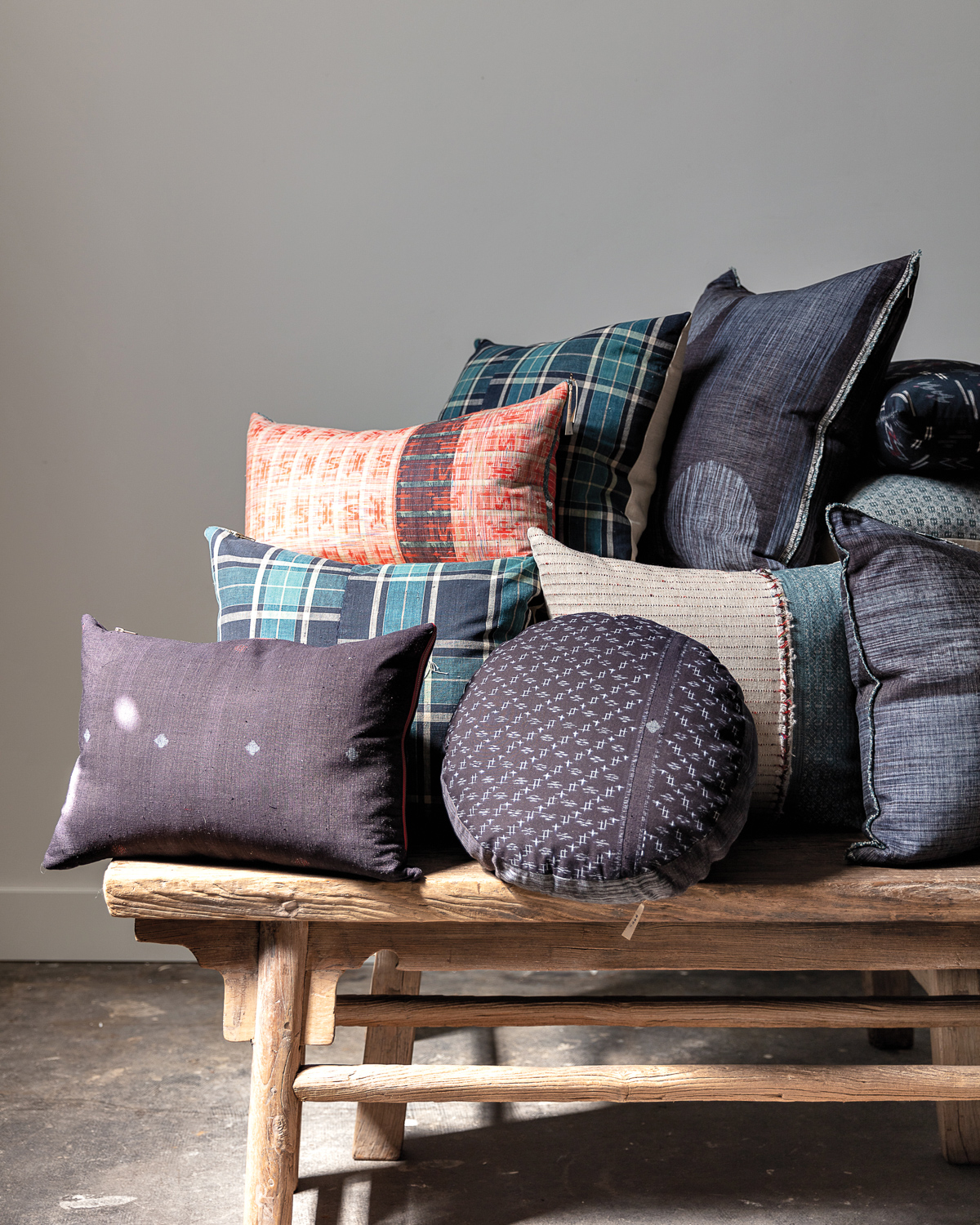 Dark blue, green and red patterned pillows atop a wooden bench.