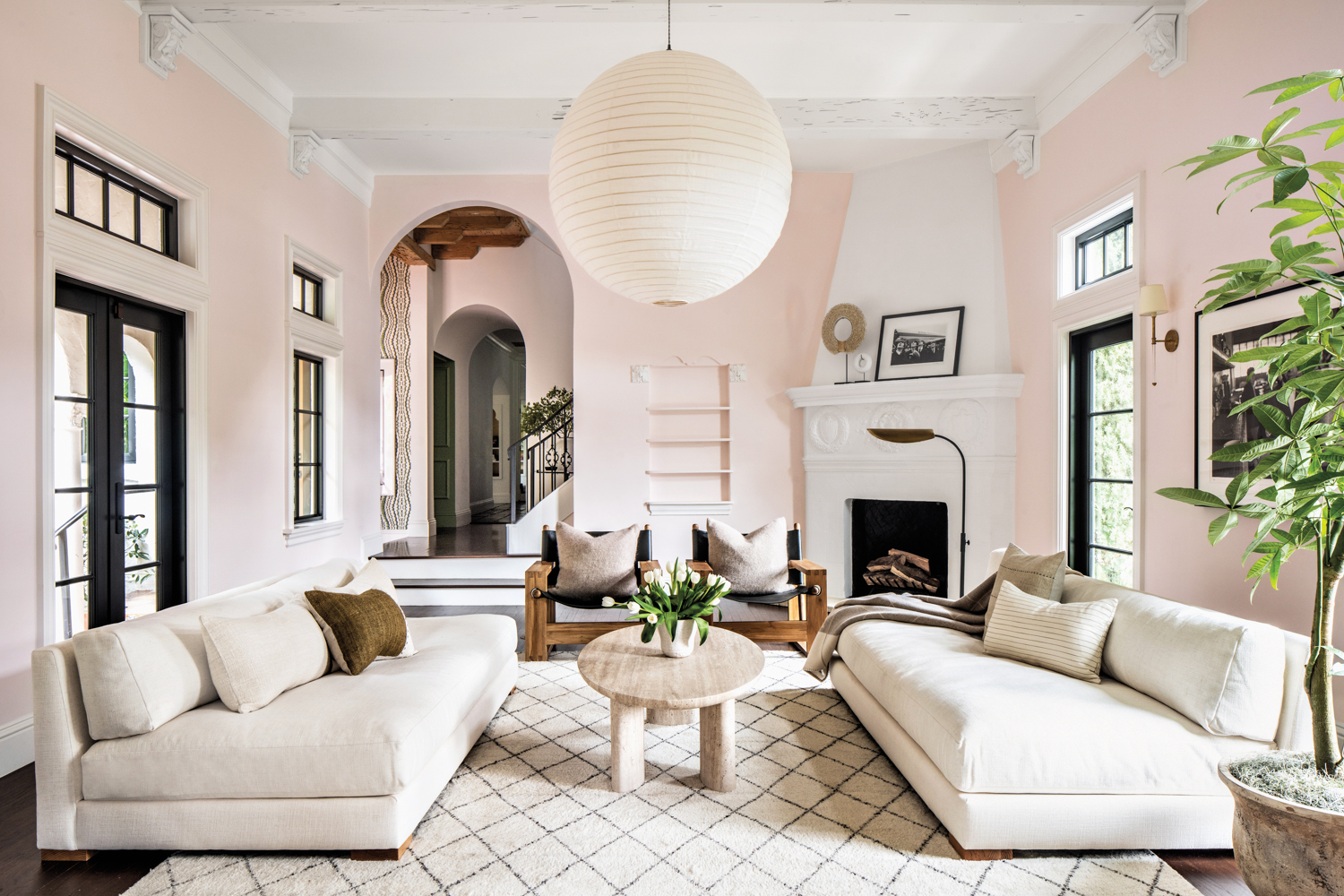 light pink living space with while couches and round lighting fixture