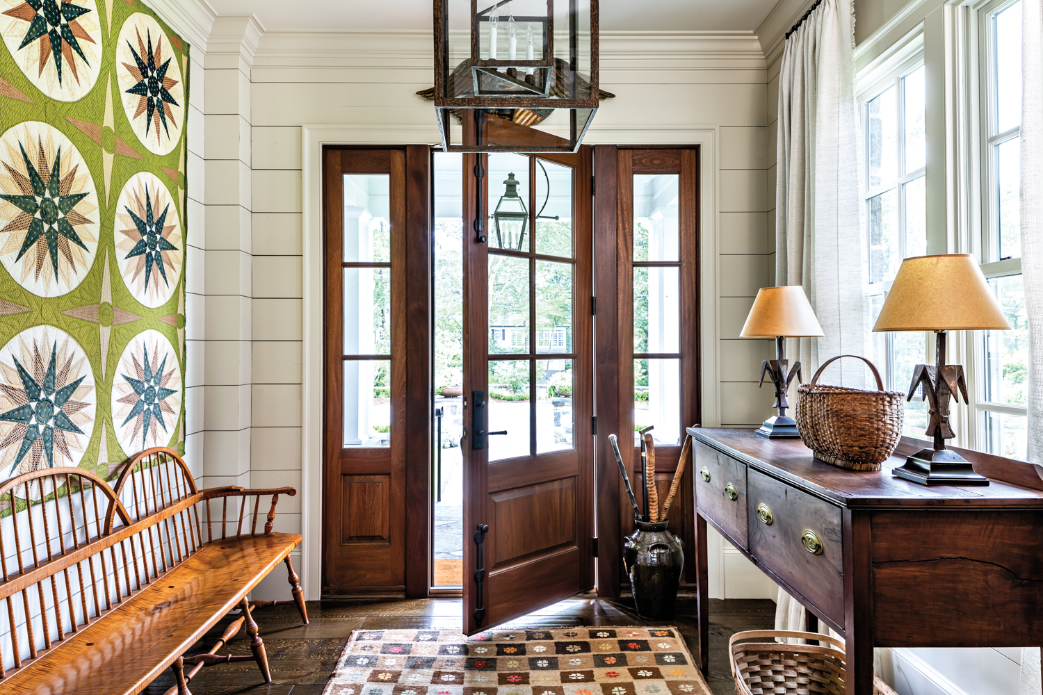 Entryway with open door, antique rug, hanging lantern and antique bench