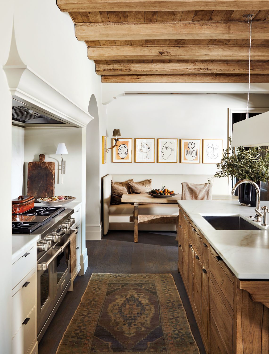 Kitchen with reclaimed wood textures, banquette seating, an antique rug and abstract artwork