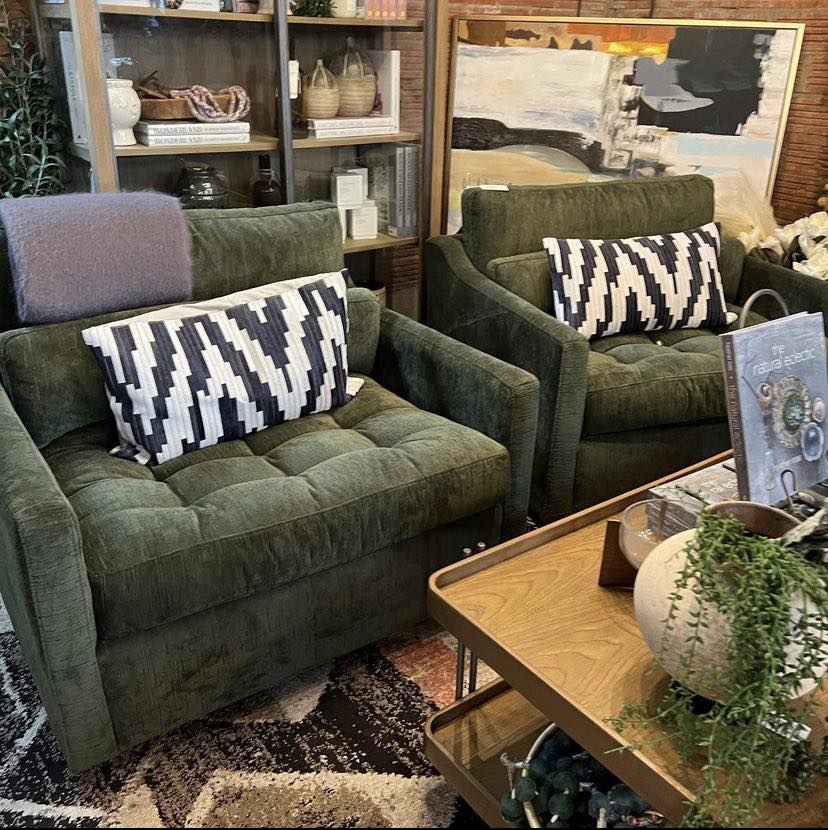 Green velvet sitting chairs with animal print accent pillows.