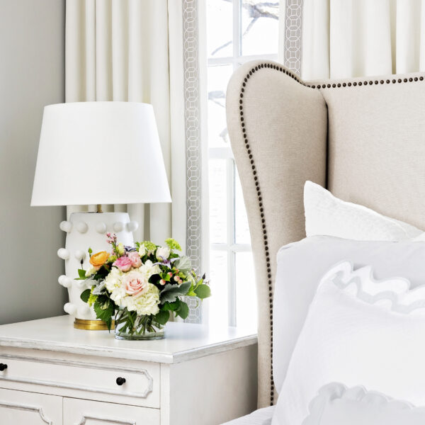 A serene bedroom showcasing a bed dressed in white sheets and pillows, accompanied by a white bed frame.