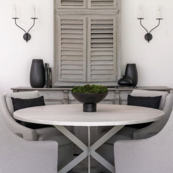 A white dining table with four chairs and a black accessories, creating a stylish and modern setting.