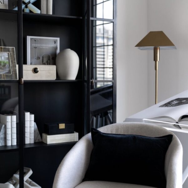 A stylish black glass-fronted bookcase filled with carefully chosen accessories, adding personality to this cozy corner nook.