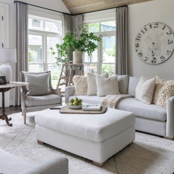 A living room with white furniture and a large clock.