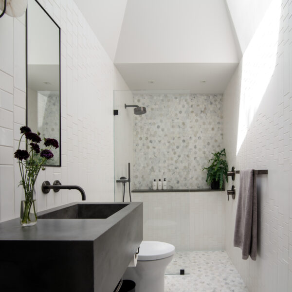 White bathroom with tile wall and high ceilings.