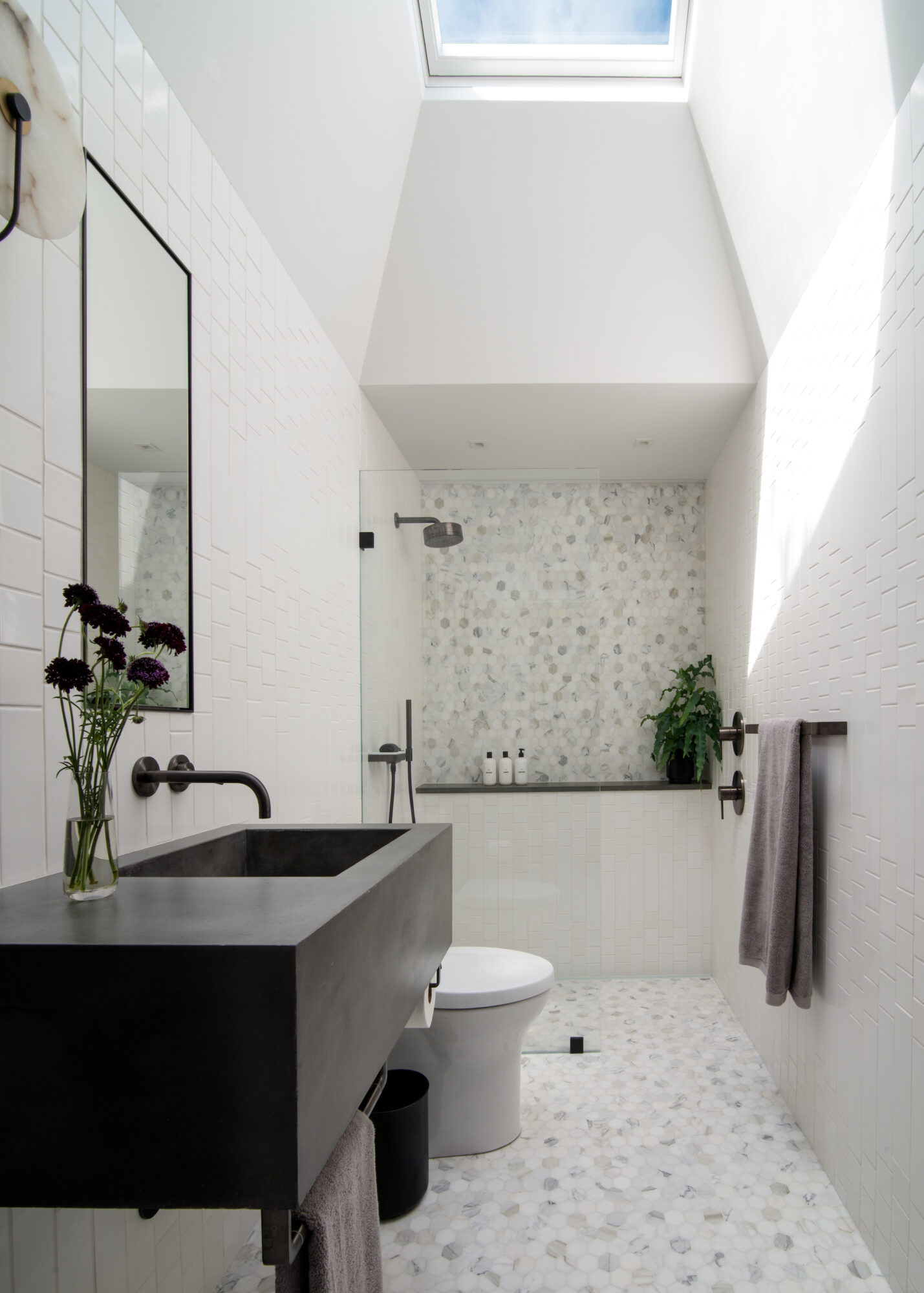 White bathroom with tile wall and high ceilings.
