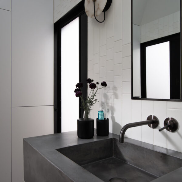 Black sink and faucet features in white bathroom.