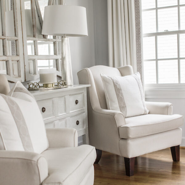A pair of upholstered armchairs styled with luxe velvet trim pillows that play off the custom draperies with leading edge trim help create a sophisticated, but inviting sitting area.