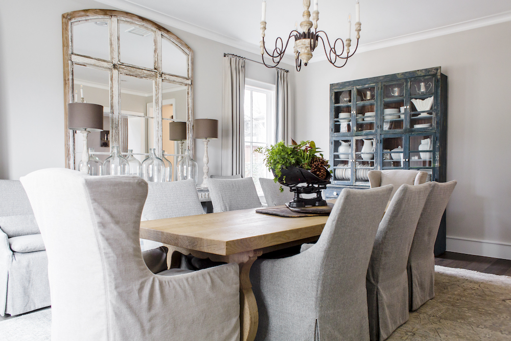 A dark blue antique china cabinet and old industrial window frame repurposed with mirrored glass create a truly one-of-a-kind dining room setting.