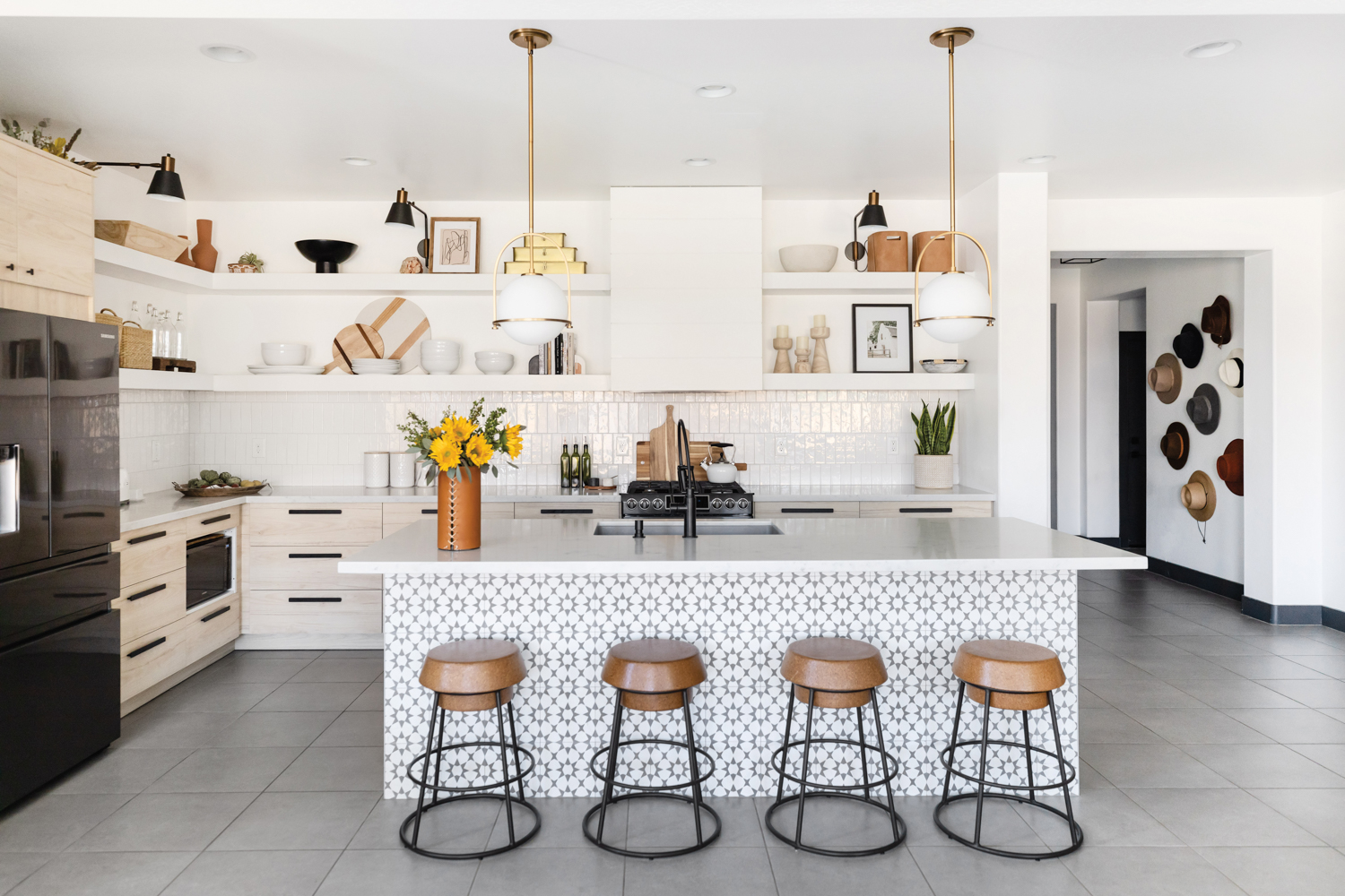 White kitchen with open shelving and geometric-patterned tile on island base.