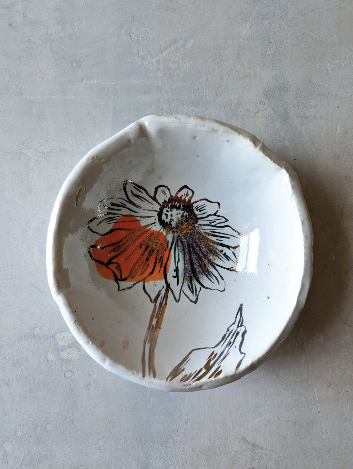 Small white ceramic dish featuring a black and red flower.