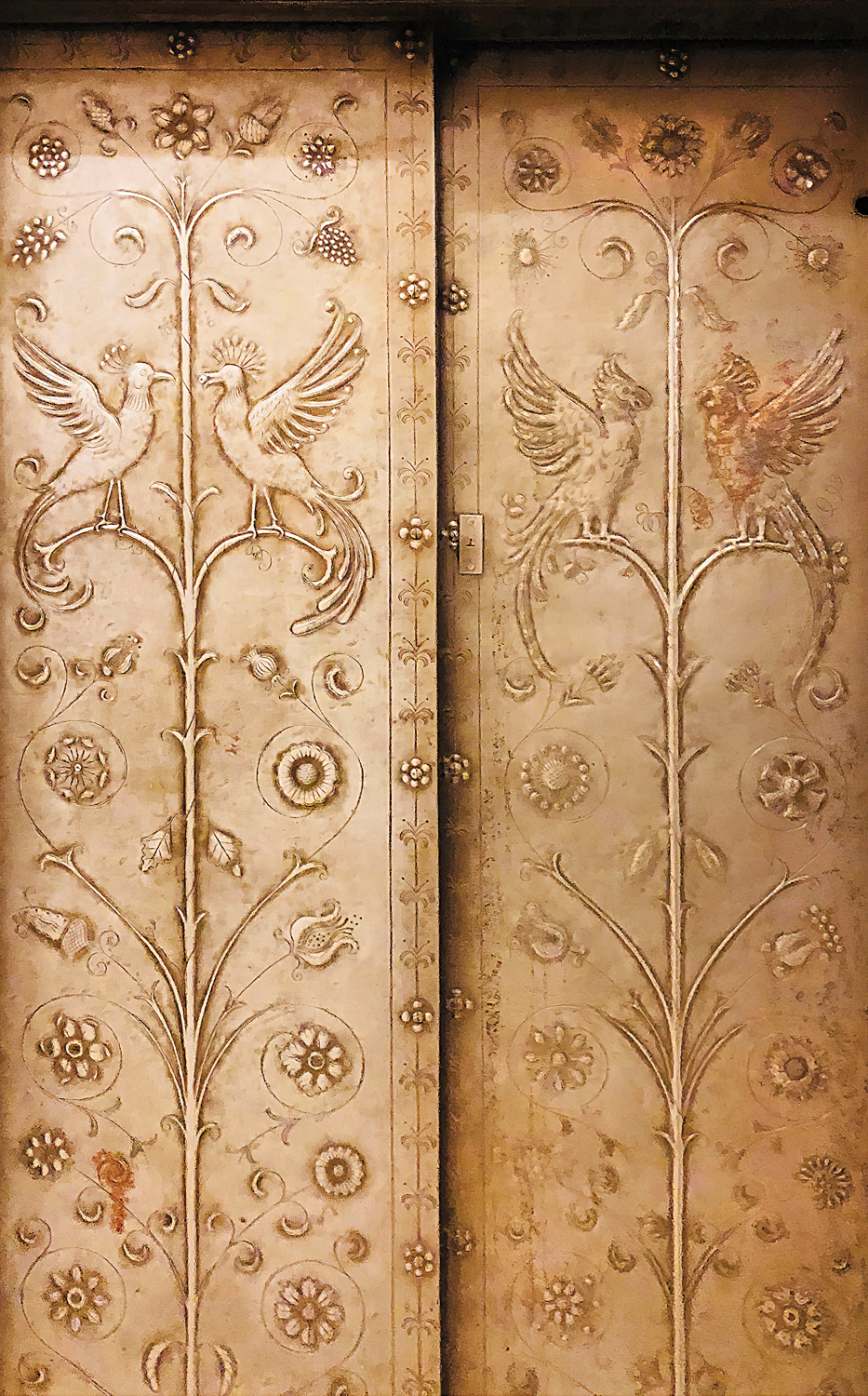 Detail shot of soft-gold panels with a bas-relief motif of birds and plants