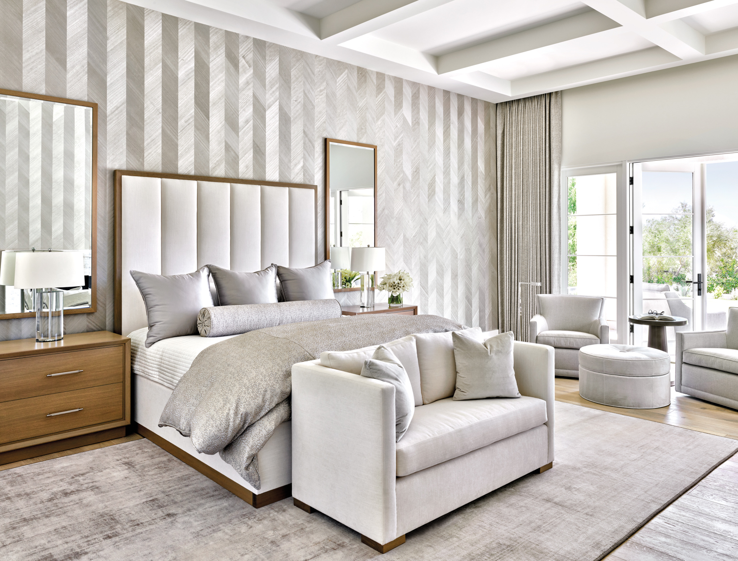 A bedroom with gray furnishings and silvery chevron wallpaper.