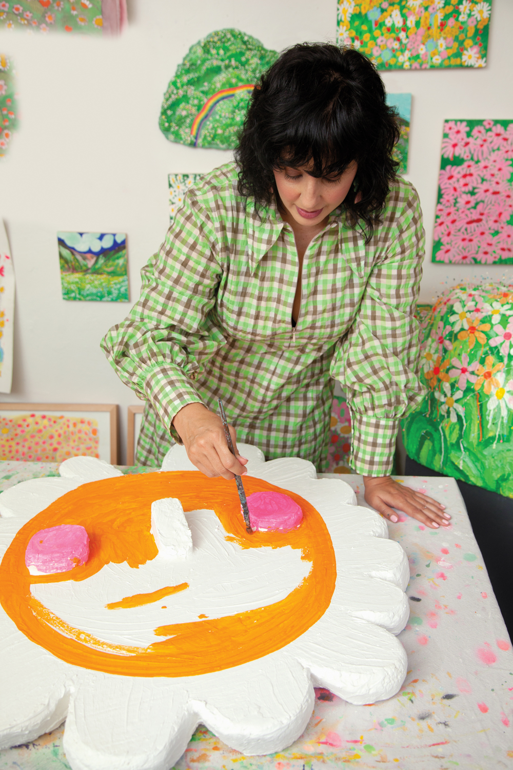 woman painting white styrofoam flower with orange paint