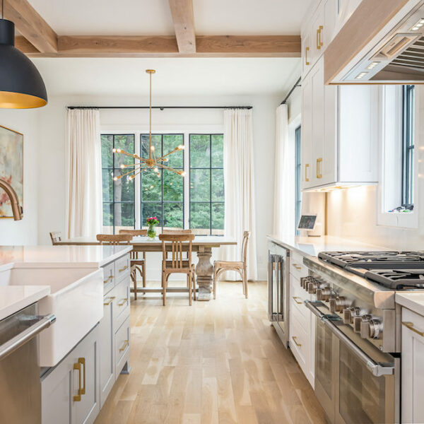 light wood floors in kitchen with white cabinets, gold fixtures and stainless steel appliances by Construction Resources in Georgia
