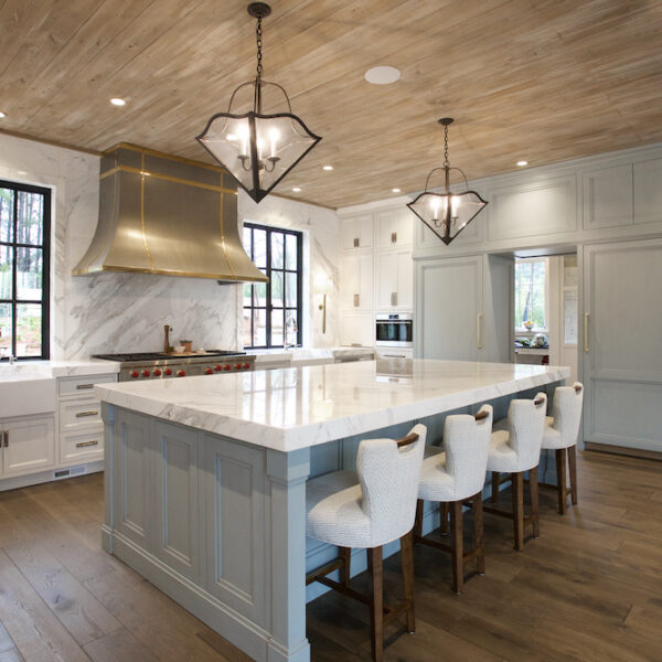 large kitchen with marble countertops, white barstools and white cabinets with black windows by Construction Resources in Georgia