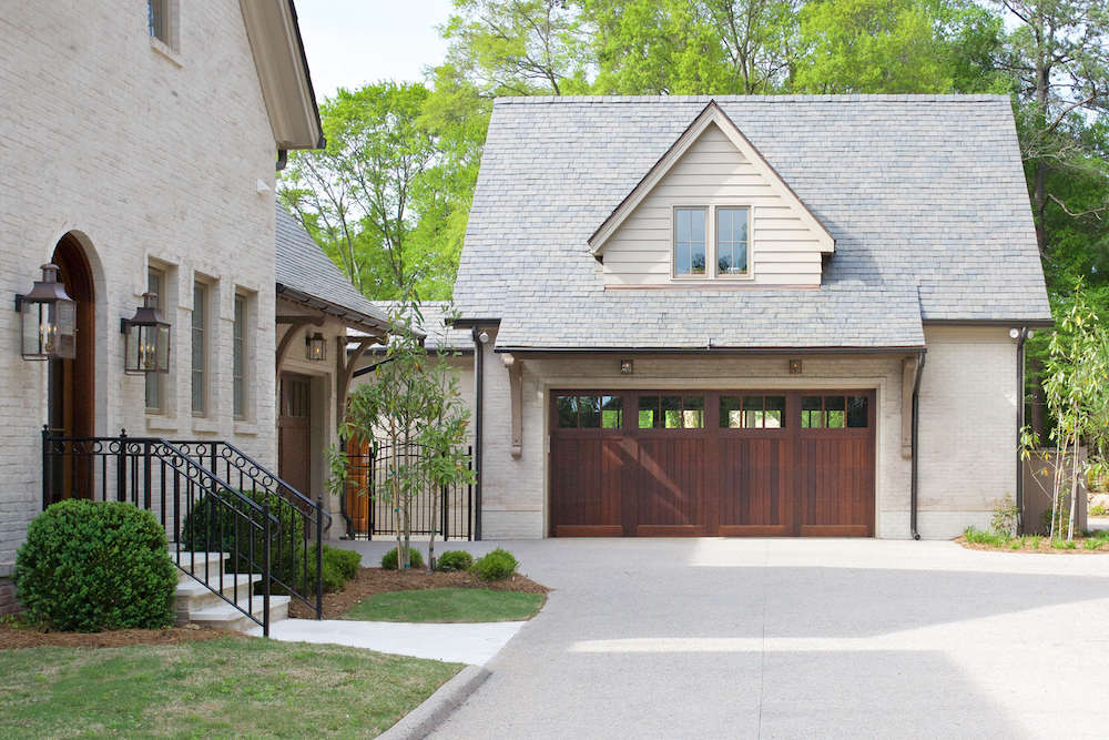 White brick house with white drive way and brown wood garage door by Construction Resources in Georgia