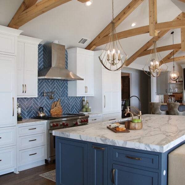 White and blue cabinets in open kitchen with wood beams by Construction Resources in Georgia