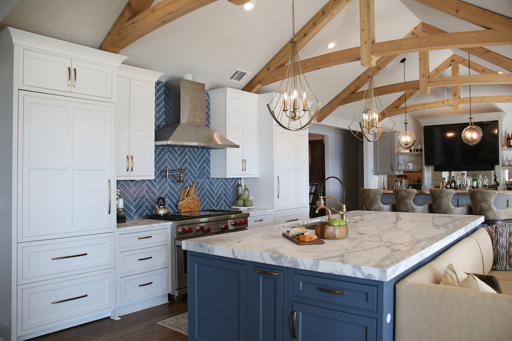 White and blue cabinets in open kitchen with wood beams by Construction Resources in Georgia