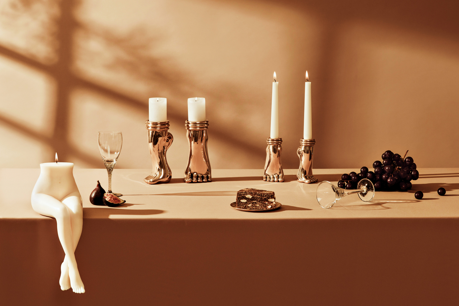 Candle shaped like a woman's crossed legs and four candleholders shaped like feet amongst other decor items