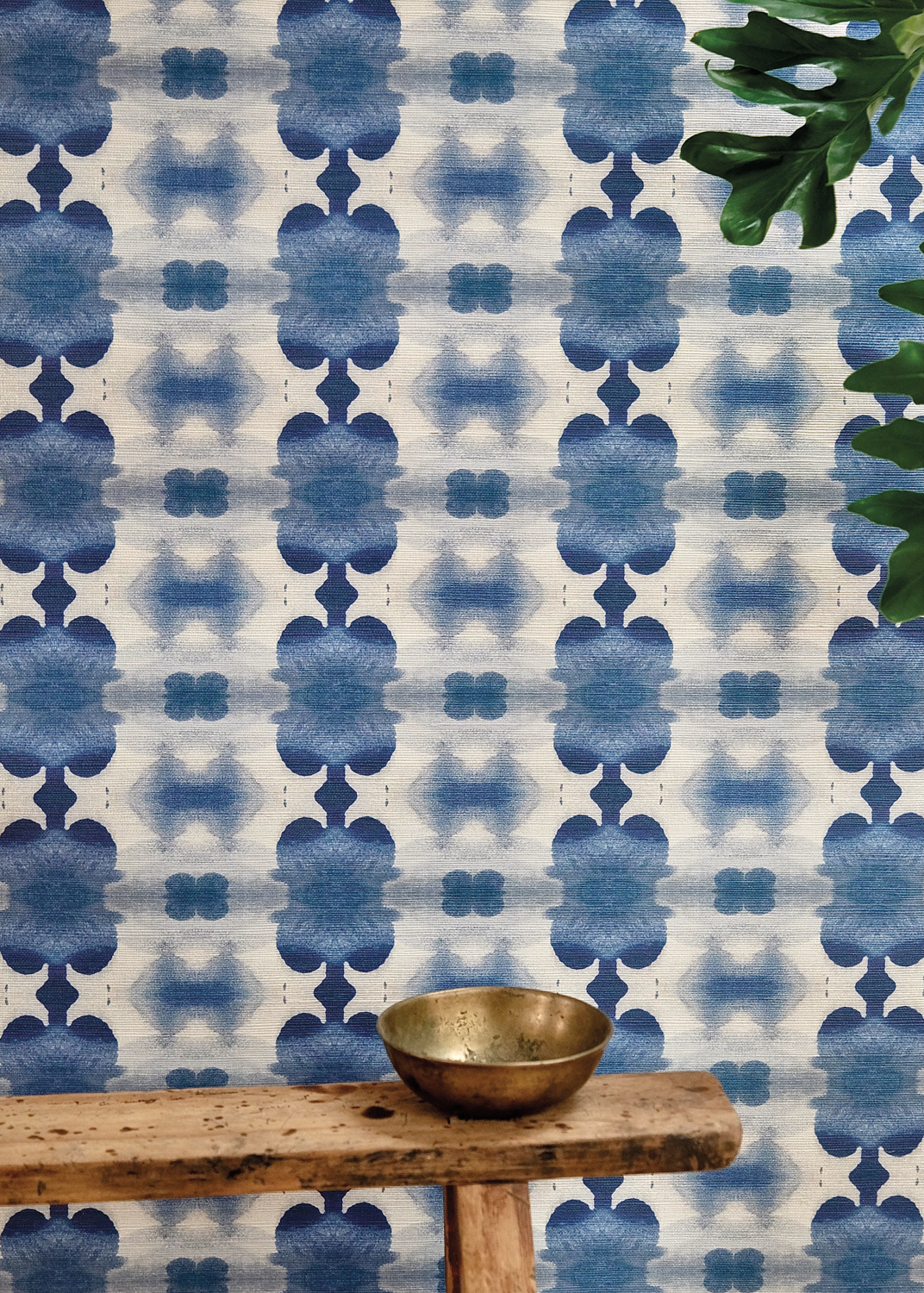 A wall covered in a blue, patterned Edie Ure wallpaper
