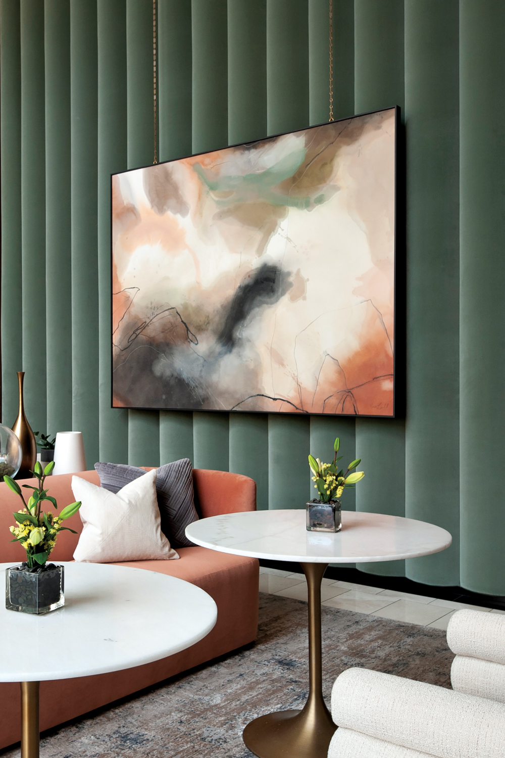 Large abstract artwork hangs against scalloped green wall in a restaurant-like seating area with peach banquette