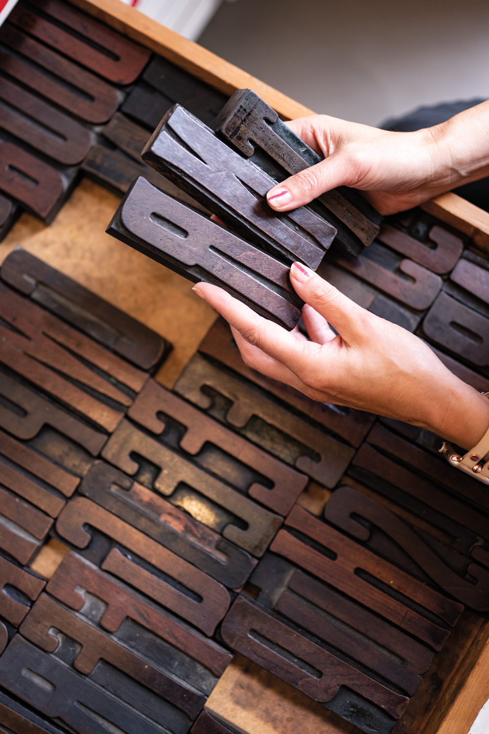 Large wooden printing blocks contain letters.