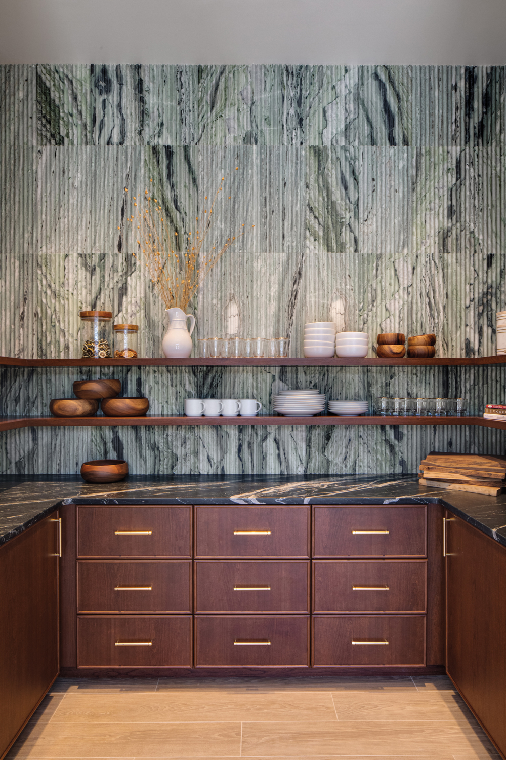 pantry with rigged-stone backsplash behind open shelves above black-and-white marble countertop 