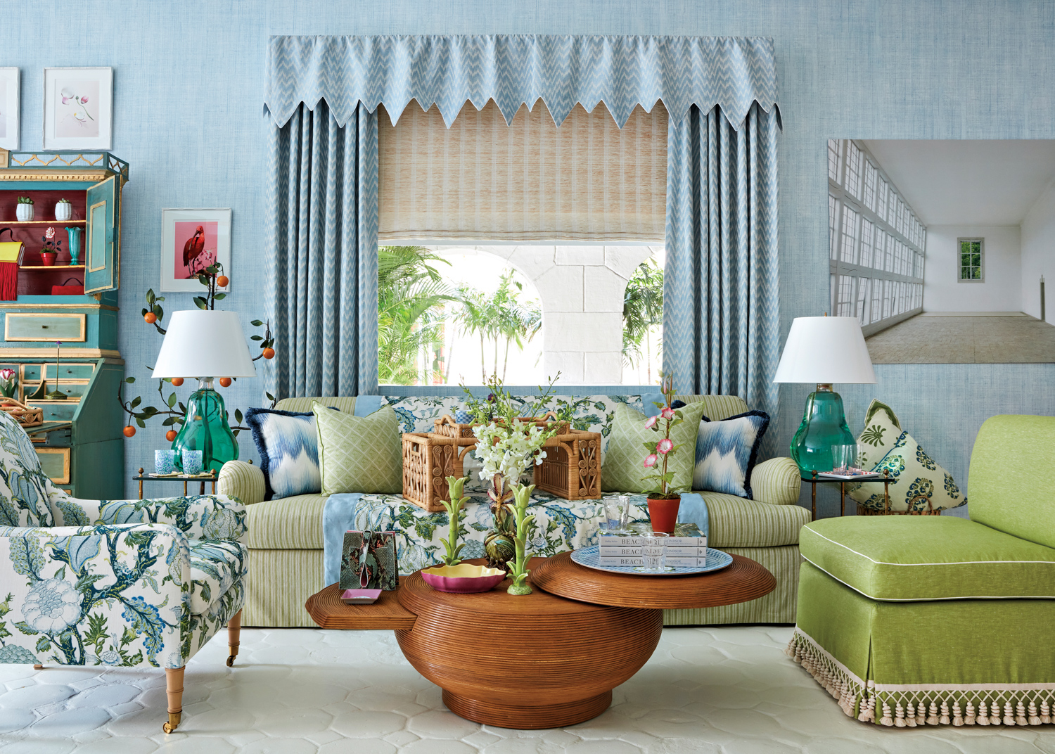 Blue wallpaper and draperies behind a green couch and floral armchair from Casa Branca Palm Beach
